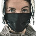 a woman wearing a black mask with feathers on it
