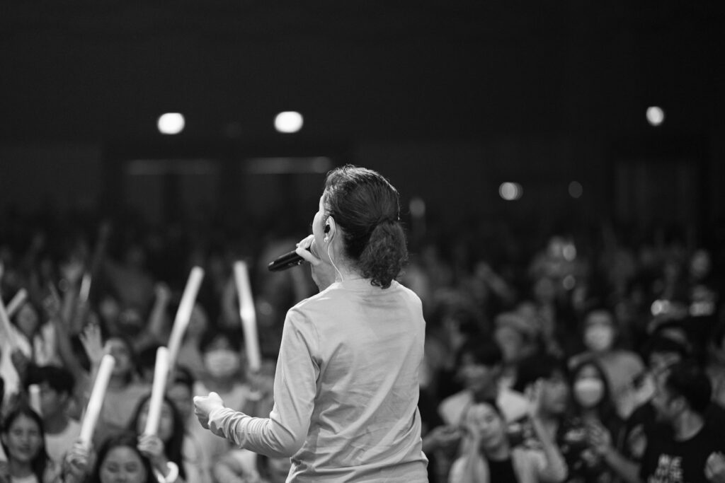 a woman standing in front of a crowd holding a microphone