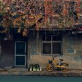 yellow bicycle parked beside gray concrete house