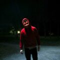 person in red pullover hooded jacket standing in street during nighttime